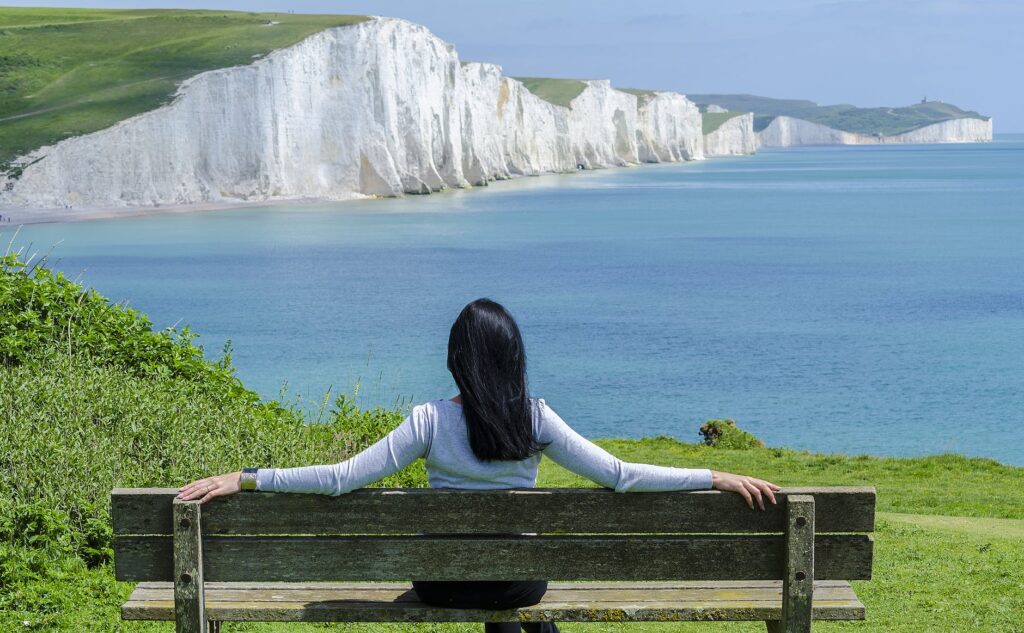 woman sitting on deck chair by sea