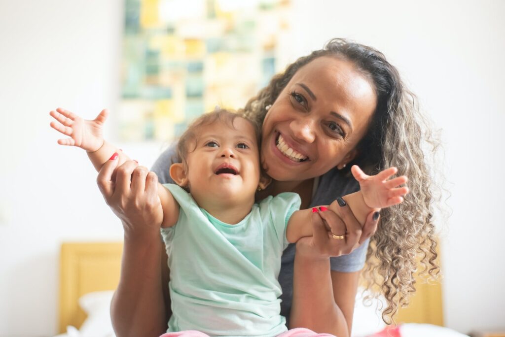 photo of a parent with curly hair playing with her baby